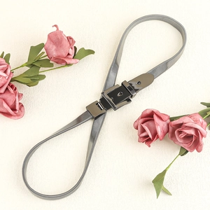 Detailed view of silver spring chain belt with a black square buckle and floral accents