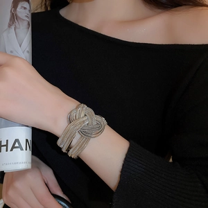 Macro shot of silver woven knot cuff bracelet with industrial metallic texture