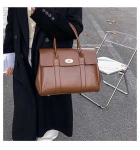 Close-up of a large brown leather tote bag with classic metal lock and high-end texture
