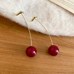 Close-up of elegant cherry drop earrings with deep red beads and golden metal hooks