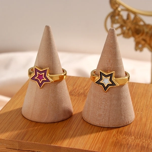 Detail view of gold boho rings with purple and black star enamel on wooden stands