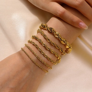 Close-up of stacked 18K gold-plated twisted rope chain bracelets on a model wrist