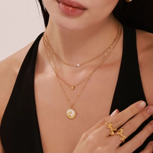 Layered gold necklace with pearl, star and round pendants styled with butterfly rings