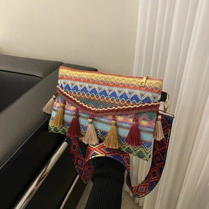 Close-up of bohemian woven envelope bag featuring colorful tassels and jacquard strap