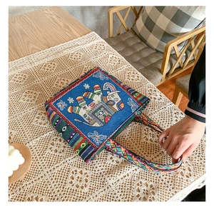 Close-up of ethnic canvas handbag featuring blue elephant embroidery and colorful woven straps