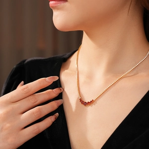 Detailed view of a gold tennis necklace featuring vibrant red gemstone v-shape pendants