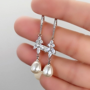 Macro detail of silver drop earrings featuring water-drop pearls and leaf-shaped zircons