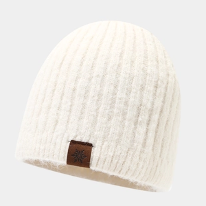 Detail of white ribbed knit beanie with brown leather snowflake patch and soft texture