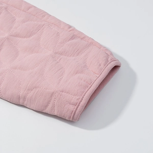 Close-up of pink quilted jacket cuff with curved petal stitching and smooth piping
