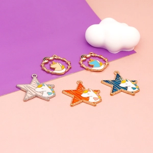 Detail of five gold unicorn charms with colorful enamel in star and round shapes