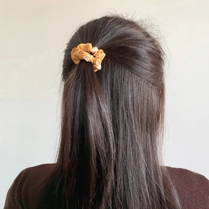 Detail of soft fabric scrunchie with orange floral patterns on long hair