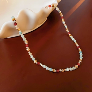 Detailed view of colorful crystal beaded necklace on a white shell-shaped plate