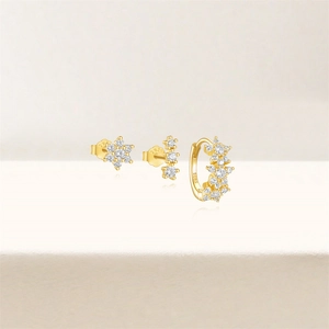 Detail of three-piece gold S925 sterling silver earring set with crystals and floral stud