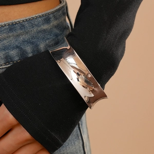 Close-up of a wide silver cuff bracelet with a polished mirror finish on woman's wrist