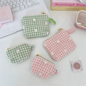 Close-up of floral gingham cosmetic bags featuring pearl zippers and woven handles