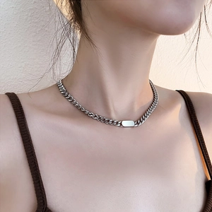 Close-up of a silver polished rectangular plaque on a sleek curb chain necklace