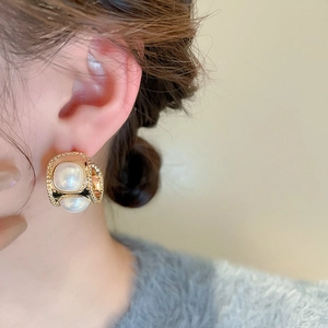 Gros plan de boucles d'oreilles vintage dorées en C avec perles d'imitation à l'oreille
