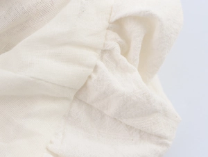 Close-up of white woven cotton-linen fabric showing detailed texture and natural pleats