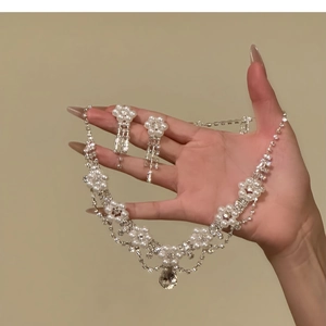 Detailed view of luxury flower jewelry set featuring pearls and teardrop crystals held by hand