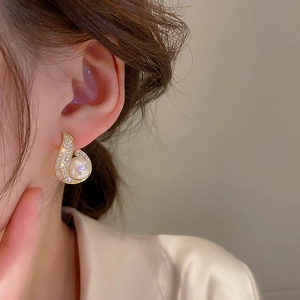 Close-up of model wearing gold mermaid tail pearl earrings with shimmering cubic zirconia