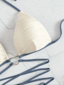 Detail of cream bikini top featuring ripple texture fabric and silver heart hardware