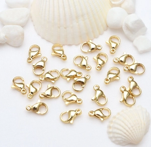 Golden 14k 18k lobster clasps for DIY jewelry making scattered on a white textured background