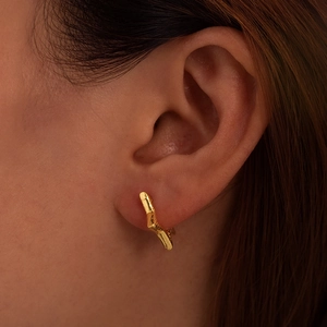 Élégantes créoles en acier inoxydable plaqué or 18 carats portées sur l'oreille du modèle