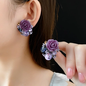 Close-up of vintage style purple rose earrings with blue and lavender crystal accents