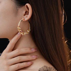 Gros plan de boucles d'oreilles créoles dorées avec zircons étincelants sur un modèle