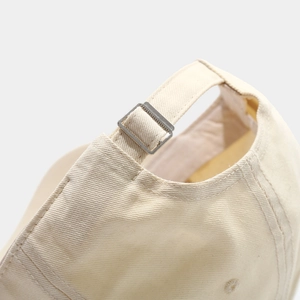 Detailed close-up of beige cotton baseball cap with adjustable metal buckle at the back