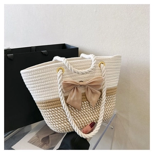 Detail of beige and khaki woven tote bag featuring thick rope handles and a large bow
