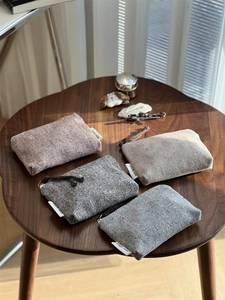 Macro detail of herringbone tweed pouches in four colors with zipper and woven puller
