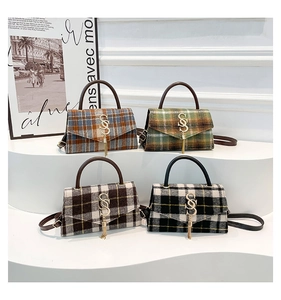 Detail view of four checkered handbags with metal S-logos and tassels on white stands