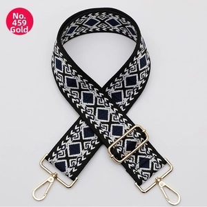 Close-up of geometric diamond pattern bag strap with gold metal hooks and buckle