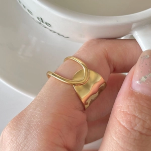 Minimalist wide gold-plated 925 silver ring with irregular wave design worn on finger