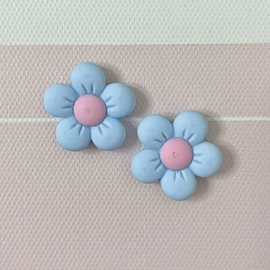 Macro shot of two light blue five-petal resin flowers with pink centers for DIY crafts
