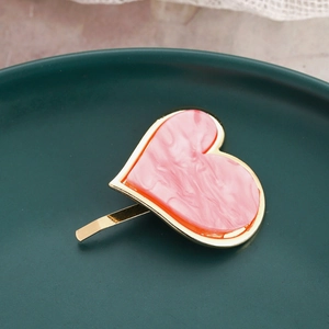 Close-up of pink marble texture resin heart hair clip with elegant golden metal frame