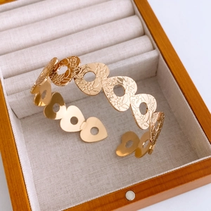 Detail shot of golden heart镂空 bangle featuring floral engraving in a luxury jewelry box