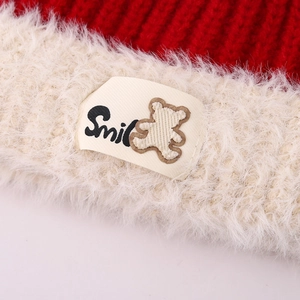 Close-up of winter knit hat featuring a Smile bear label and plush fleece trim detail