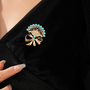 Detail of vintage gold fan brooch with blue beads and crystals on black fabric