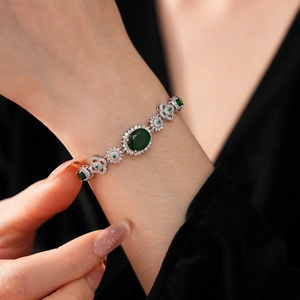 Close-up of vintage flower bracelet with emerald-green stones on a model's wrist