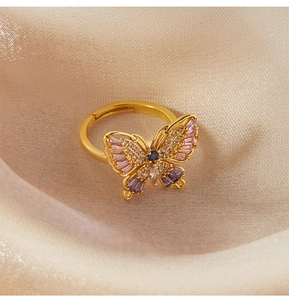 Detailed close-up of a golden butterfly ring with pink and purple gems on champagne silk