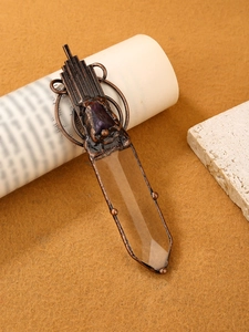Detailed macro view of vintage bronze pendant featuring clear crystal and raw amethyst stone