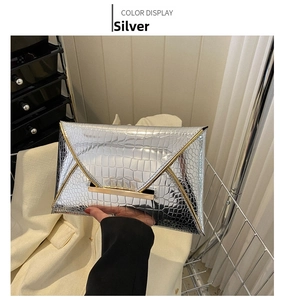 Detail view of silver crocodile embossed envelope clutch with golden metal trim