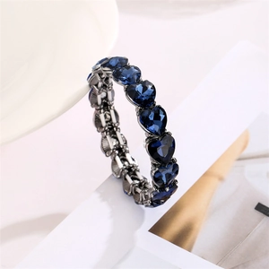Detailansicht von blauen Kristallherzen in dunklem Metall auf einem elastischen Armband