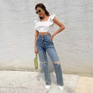 White ruffle sleeve backless top paired with blue ripped jeans and green accessories