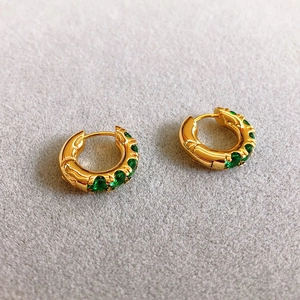 Detailed side view of golden hoop earrings featuring micro-set green zircon gemstones
