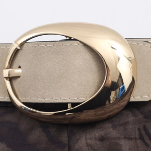 Close-up of beige leather belt with a large polished golden oval buckle and stitching