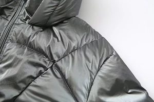 Close-up of metallic dark grey puffer jacket showing glossy fabric and shoulder stitching