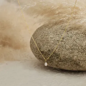 Detailed close-up of a teardrop freshwater pearl pendant on a fine 18K gold-plated chain